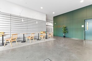A modern interior with a reception area, a green wall with the word "LUMOS" on it, and a seating area with tables and chairs. - 1 Bed |Balcony| Near Down town (Minneapolis)