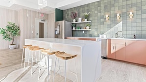 Een moderne keuken met een centraal eiland, een bar met barkrukken, roestvrijstalen apparatuur en sierplanten.