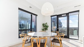 Een moderne eetruimte met een ronde tafel en zes stoelen, grote ramen en een hanglamp.