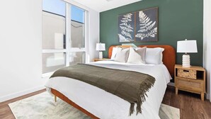 A modern bedroom with a large bed, a green accent wall, and a large window. - 1Bed Apt, Gym | Lowry Hill | Theater (Minneapolis)