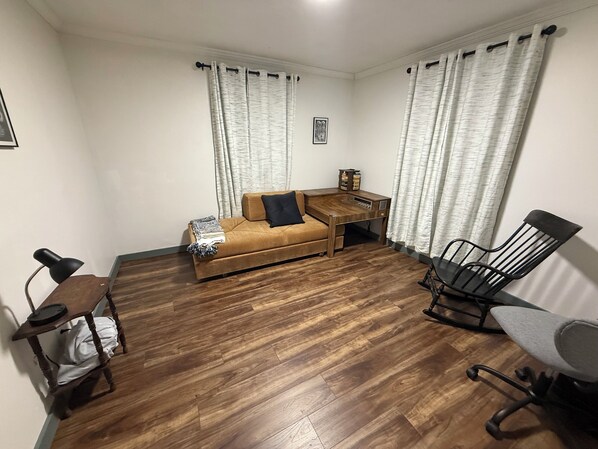 Un espacio habitable compacto con un sofá, una pequeña mesa de centro, un escritorio con una silla y una mesa de comedor con una silla.