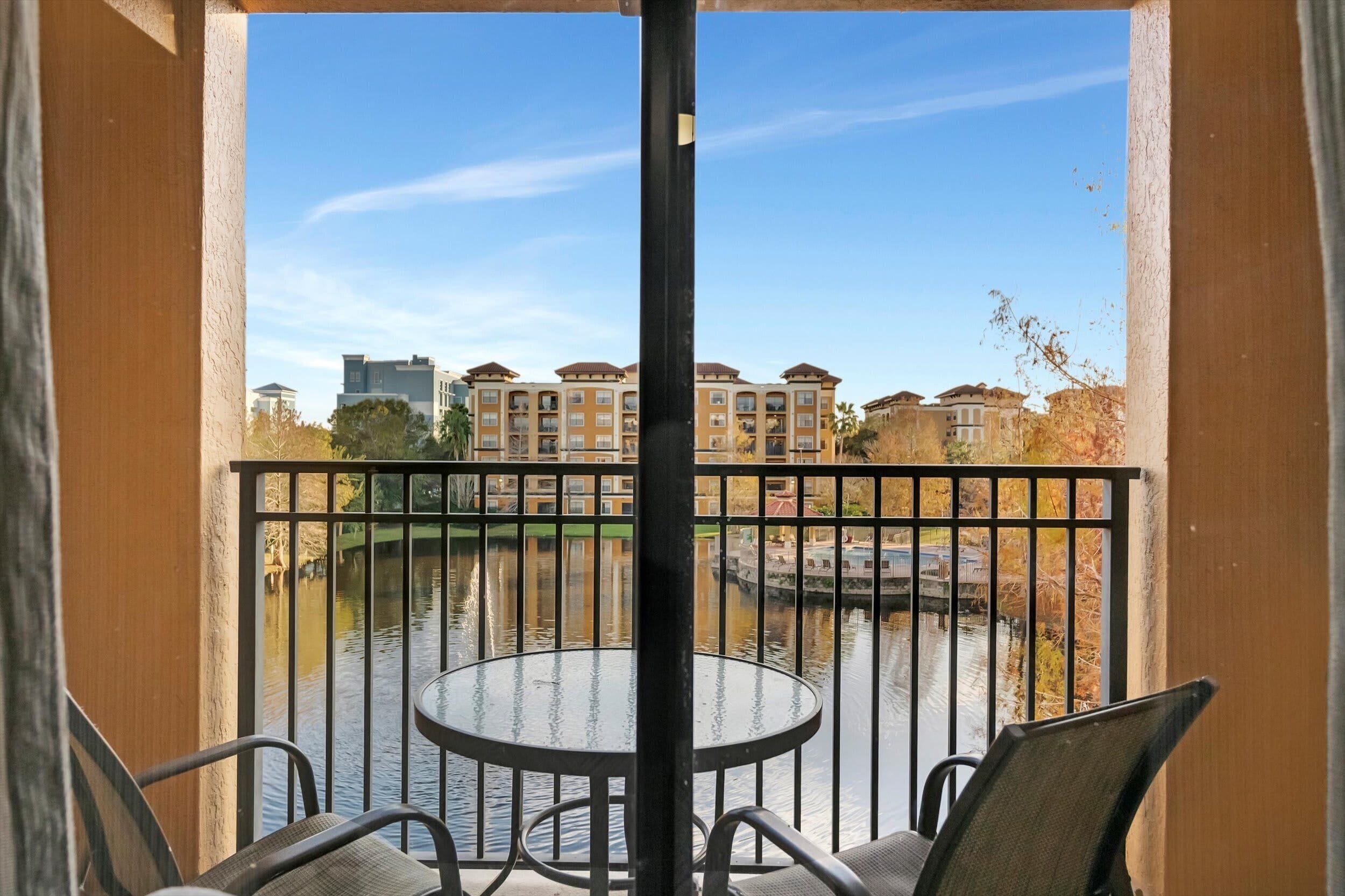 Een balkon met uitzicht op een gracht en gebouwen op de achtergrond.