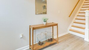 Un couloir avec une console en bois, un miroir et un escalier.