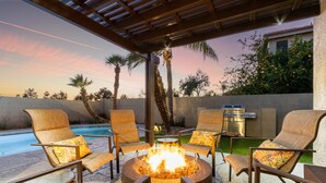 Eine Terrasse mit Feuerstelle, umgeben von Stühlen und einem Pool.