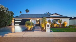 A modern house with a garage, a well-maintained lawn, and a driveway. - Sol Paradise Villa -Private Pool, Games, BBQ, wet bar & EV charger (Scottsdale)