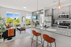 A modern kitchen with a central island, stainless steel appliances, and pendant lighting. - 1BR Apt | Rooftop, Gym, Workspace (Minneapolis)