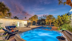 Una vasca idromassaggio con piscina, area relax all'aperto e palme.