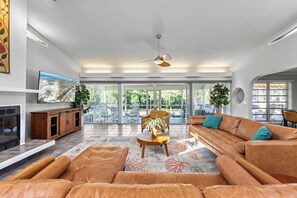 Ein geräumiges Wohnzimmer mit einer Ledersofa, einem Holztisch und einem Fernseher an einer weißen Wand.