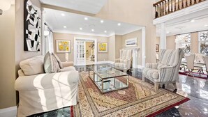 Un salón espacioso con una mesa de centro de cristal, sofás cómodos y alfombras estampadas.