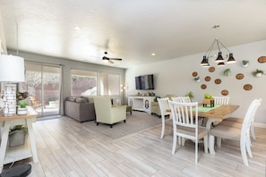 A spacious living area with a dining table, chairs, a sofa, and a ceiling fan.