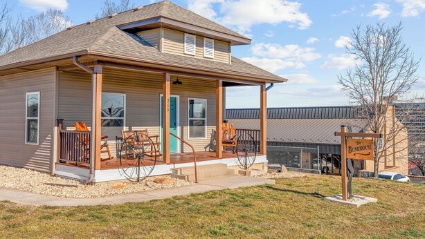 A two-story building with a porch, a sign reading "The Bunkhouse," and a covered outdoor seating area. - The Bunkhouse | Downtown Branson Home Walkable to Landing & Convention Center (Branson)
