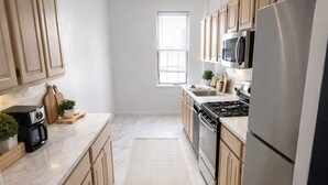 Eine moderne Küche mit Holzausstattung, einem Edelstahlkühlschrank, einem Gasherd und einer Mikrowelle.