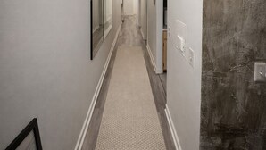 Ein Flur mit einer Leuchte, einem Teppich und einer strukturierten Wand.