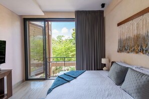 A bedroom with a bed, a TV, a balcony with a view, and a wall-mounted macrame piece. - Corasol | Contemporary Design in the Jungle (Playa del Carmen)