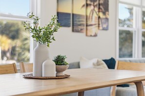 Ein Esstisch mit einer Vase und einer kleinen Pflanze auf einer gewebten Tischmatte.