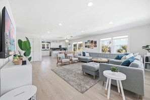 Ein modernes Wohnzimmer mit einem grauen Ecksofa, einem runden Couchtisch und einem weißen Teppich.