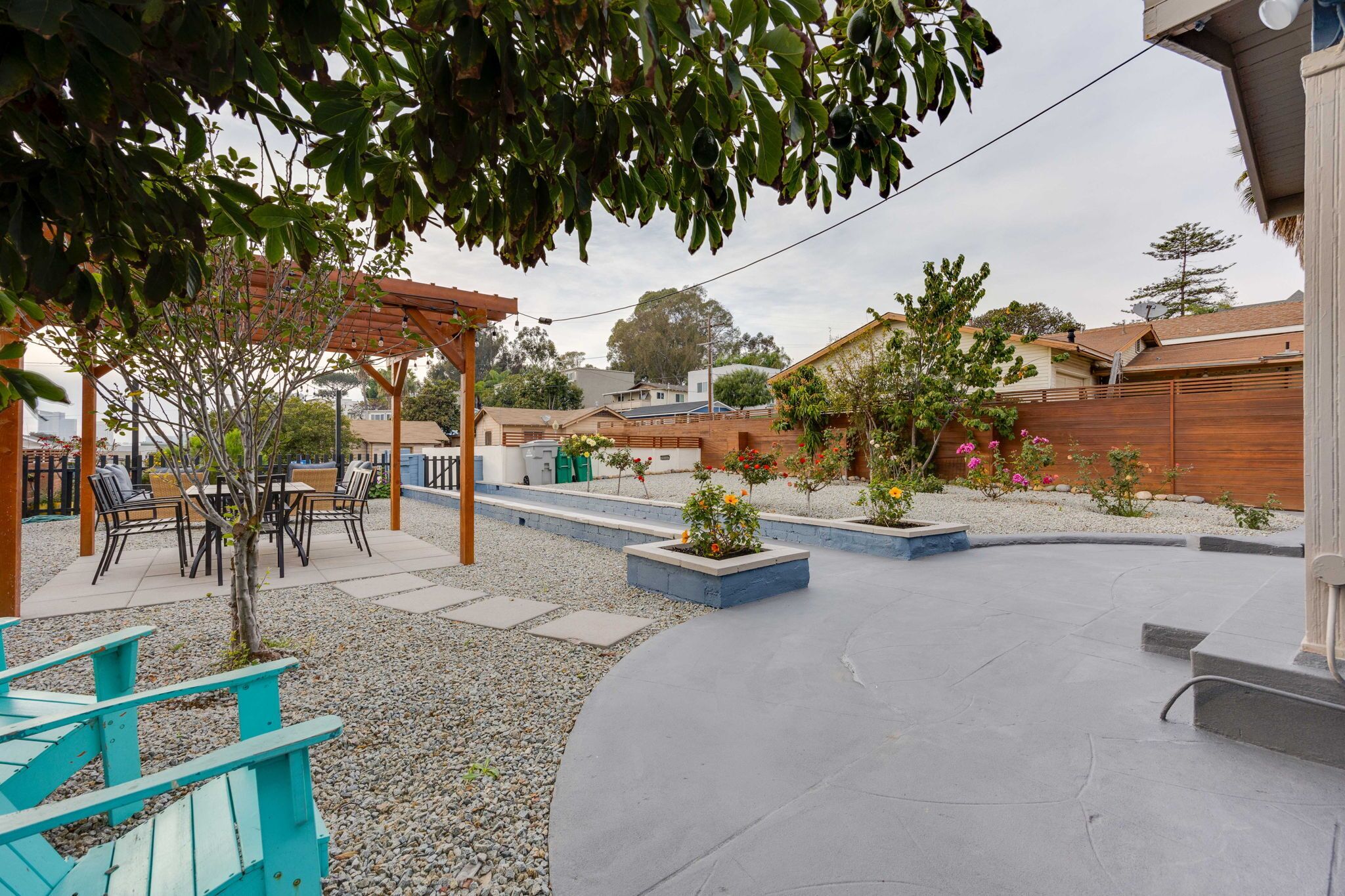 A patio area with a pergola, outdoor seating, and a garden with various plants and flowers.