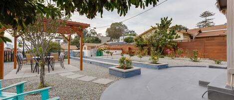 A patio area with a pergola, outdoor seating, and a garden with various plants and flowers.