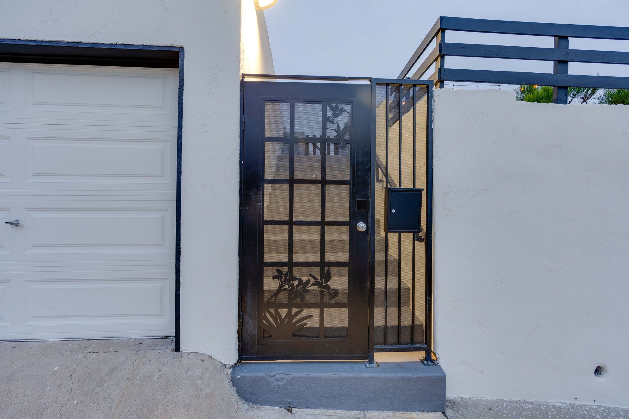 Una puerta de garaje y un acceso con portón, decorado con un panel ornamental.