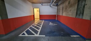 A parking garage with red and blue walls, a wheelchair-accessible path, and a door leading to another area. - Cozy and modern 1-bedroom apartment with AC in Santiago near to metro (Santiago)