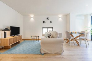 Ein modernes Wohnzimmer mit einer Couch, einem Fernseher und einem Essbereich.