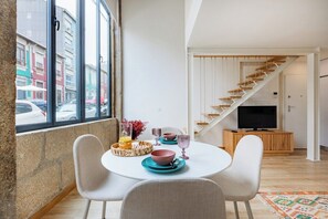 Ein modernes Interieur mit Essbereich, Treppe und Fernseher.