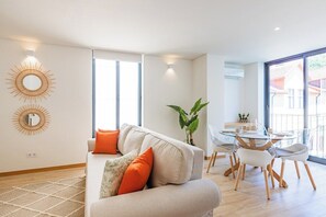 Ein modernes Wohnzimmer mit einer Couch, einem Esstisch, Stühlen und einem großen Fenster.