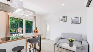 A modern living room with a grey sofa, a coffee table, and a dining area with a glass-top table and chairs. - Holiday apartment with wellness facilities and shared swimming pool (Novi Vinodolski)