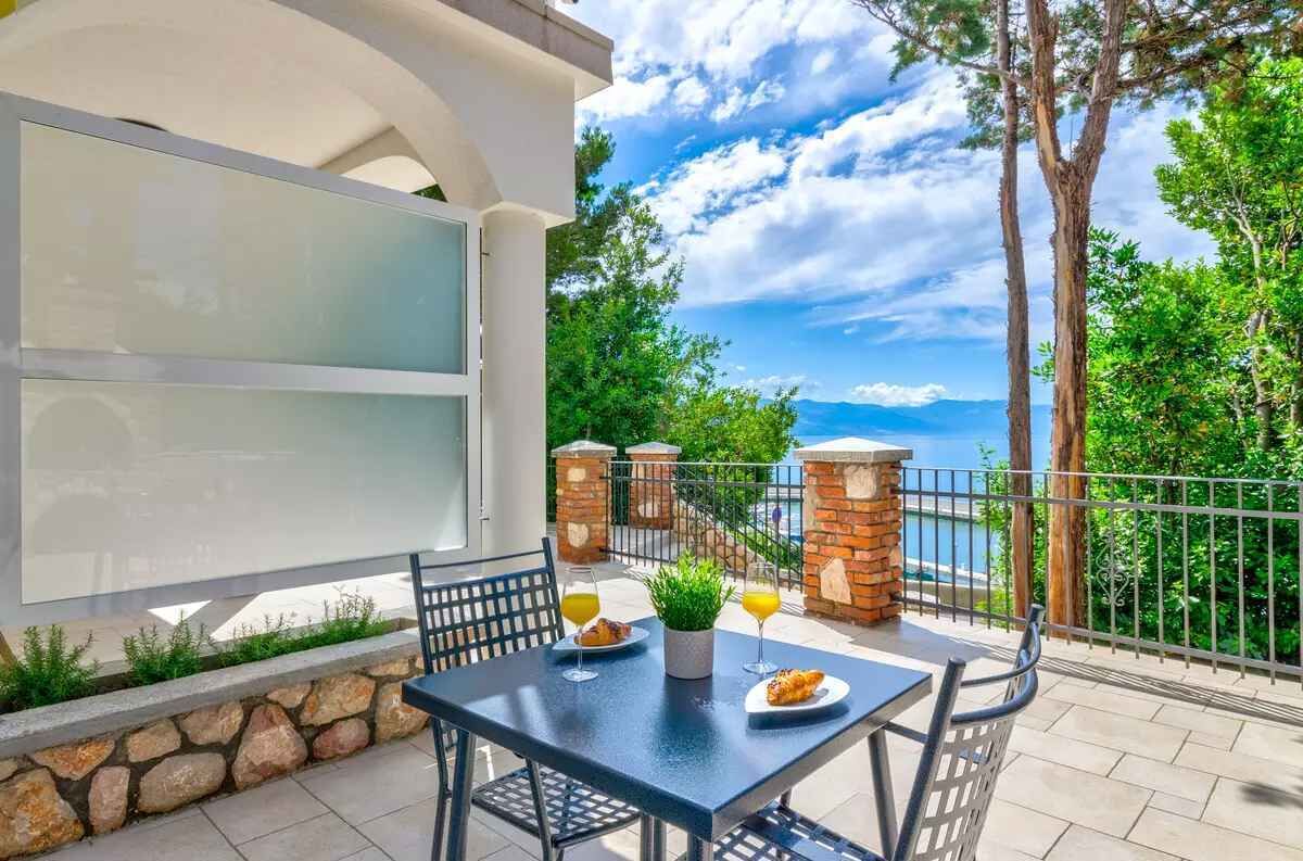 Ein Balkon mit Tisch für zwei Personen, einem Blumentopf und einem Glas Orangensaft.