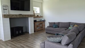 A modern living room with a grey sectional sofa, a flat-screen TV mounted on the wall, and a wooden coffee table. - “Room for Everyone: Seven-Bedroom Lakefront Getaway on Lake Tillery” (Norwood)