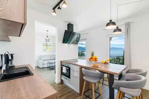 A modern kitchen with a wooden island, bar stools, and a view of the outdoors. - Holiday apartment with wellness area and swimming pool for shared use (Novi Vinodolski)