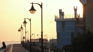 Een promenade aan het water met een rij lantaarns en een gebouw met een balkon.