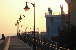 A waterfront promenade with a row of street lamps and a building with a balcony. - Holiday apartment 220 m to the beach (Porto Santa Margherita)