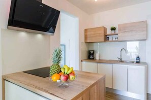 A modern kitchen with a wooden countertop, a fruit bowl, a coffee maker, and a built-in TV. - Holiday apartment with wellness facilities and shared swimming pool (Novi Vinodolski)
