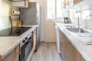 Una cocina compacta con estufa, horno, lavavajillas y pileta.