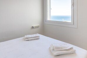 Una habitación con una cama, un ventanal con vista al mar y un enchufe en la pared.
