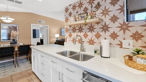 A modern kitchen with white cabinetry, a double sink, and a decorative backsplash. - The Western Bungalow - old town - bike path - pool (Scottsdale)