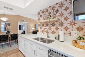 A modern kitchen with white cabinetry, a double sink, and a decorative backsplash. - The Western Bungalow - old town - bike path - pool (Scottsdale)
