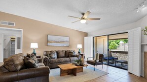 A living room with a brown leather sofa, a wooden coffee table, and a ceiling fan. There is a sliding glass door leading to an outdoor patio. - The Western Bungalow - old town - bike path - pool (Scottsdale)