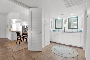 A modern kitchen with white cabinets, a dining area with a table and chairs, and a bathroom with a sink and mirrors. - The Western Bungalow - old town - bike path - pool (Scottsdale)