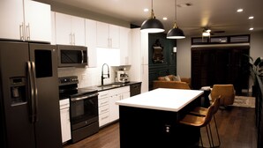 A modern kitchen with stainless steel appliances, a central island, and pendant lighting. - Private Rooftop Skyline Views - Walk To Pearl (San Antonio)