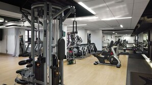 Un gimnasio moderno con diversos equipos de ejercicio, incluyendo cintas de correr, elípticas y máquinas de pesas.