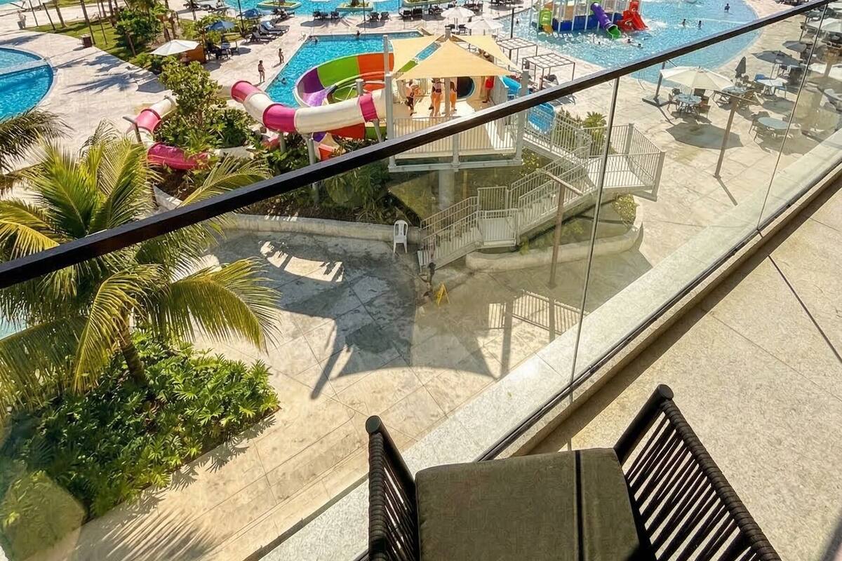 A resort with multiple swimming pools, palm trees, and a view of the ocean.