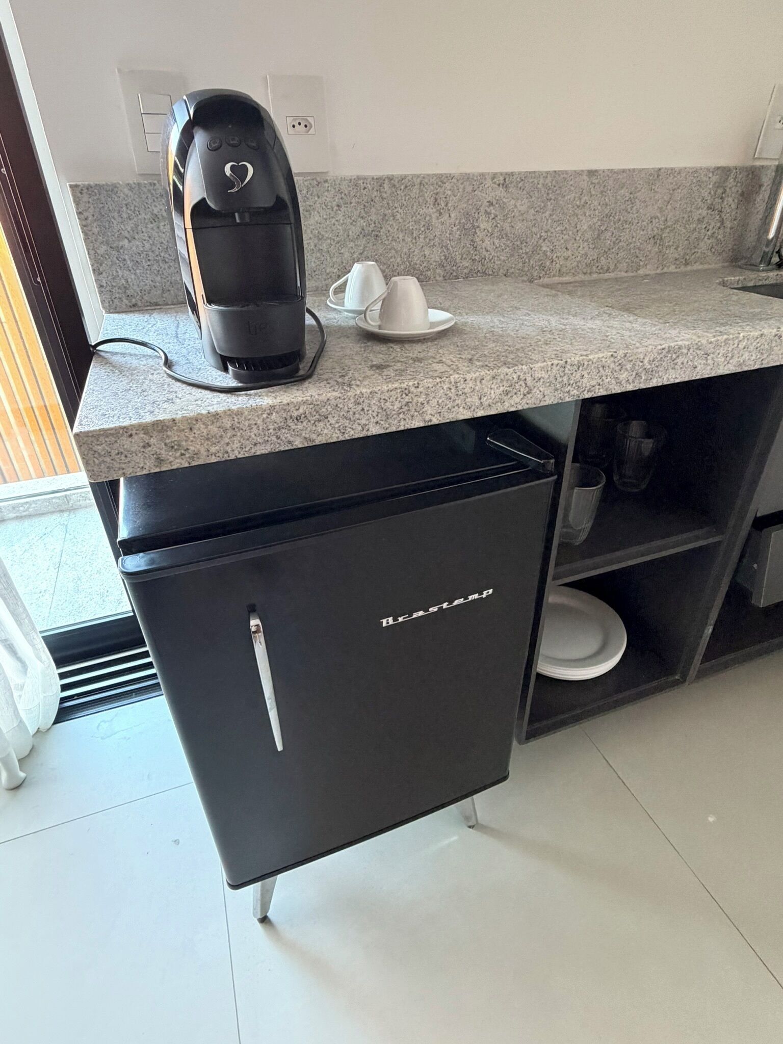 A kitchen with a coffee maker, a mini fridge, and a countertop.