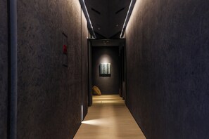 A narrow hallway with a wooden floor, dark walls, and a ceiling with recessed lighting. - Arima Hot Spring nebi (Kobe)