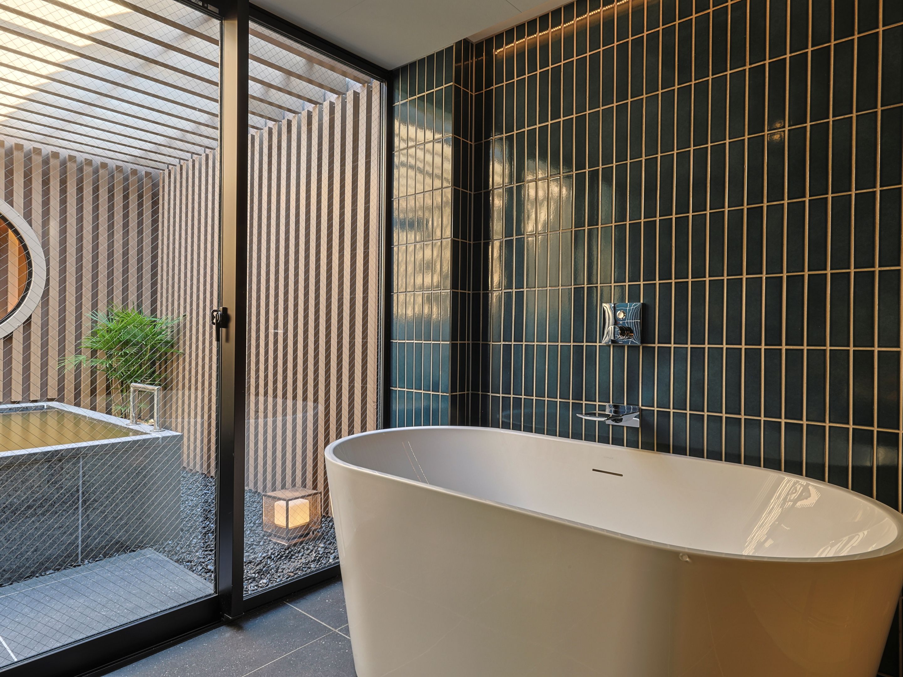 A modern bathroom with a freestanding bathtub, a glass shower enclosure, and a vertical garden.