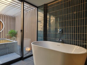 A modern bathroom with a freestanding bathtub, a glass shower enclosure, and a vertical garden. - Arima Hot Spring nebi (Kobe)