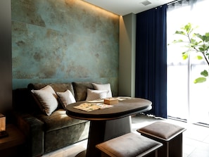 A modern living area with a sofa, a round table, and a bench. - Arima Hot Spring nebi (Kobe)