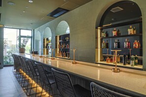 A bar area with a long counter, multiple seating options, and a variety of bottles on shelves. - Arima Hot Spring nebi (Kobe)