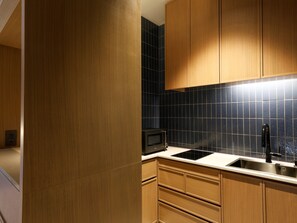 A modern kitchen with wooden cabinets, a black microwave, and a stainless steel sink. - Arima Hot Spring nebi (Kobe)